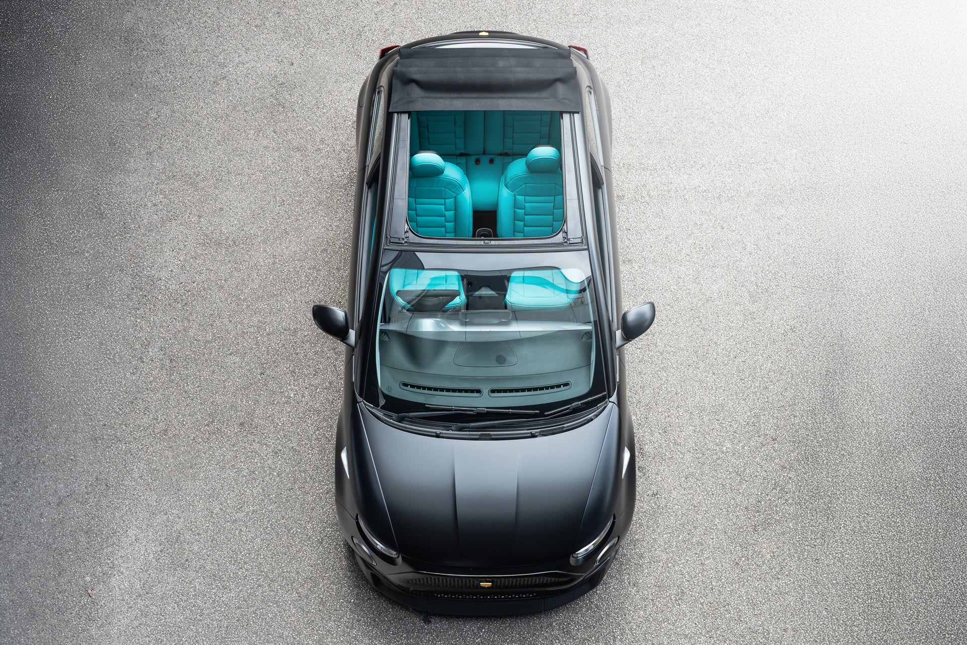 Designio Fiat 500e in Satin Black, top-down bird's eye view showing teal interior